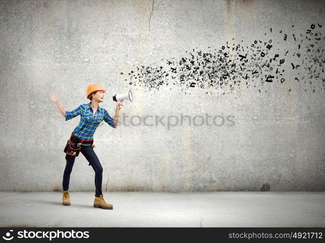 Woman builder. Young woman builder in hardhat screaming in megaphone