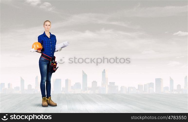 Woman builder. Young woman builder with hardhat and papers in hands