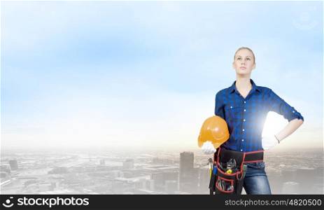 Woman builder. Young woman builder with hardhat in hands