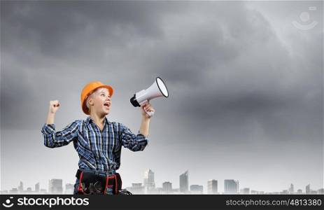 Woman builder. Young woman in hardhat screaming in megaphone