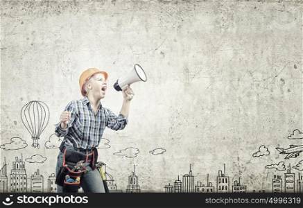 Woman builder. Young woman in hardhat screaming in megaphone
