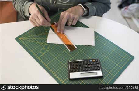 woman busy on a desk with calculating and drawing special designs from paper with green pencil and on a white desk. woman busy on a desk with calculating and drawing special designs from paper