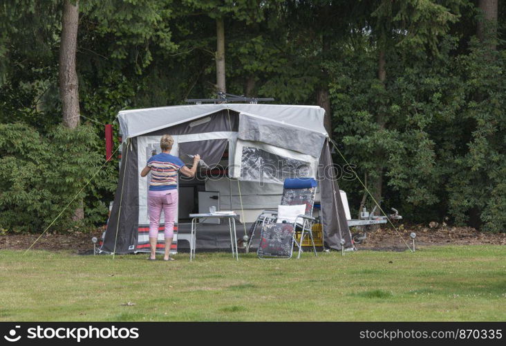 woman busy with installing a roof trailer or folding caravan on a camping in the forest. woman installing the a roof caravan on a camping