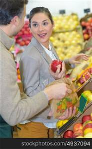 Woman buying apples, talking to grocer