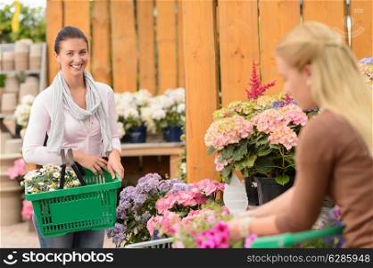 Woman buying flowers in garden center carry shopping basket smiling