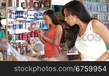 Woman buying lipstick in cosmetics store, seller serve customer in the background