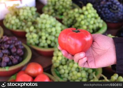 Woman buying ripe tomatoes at local market.