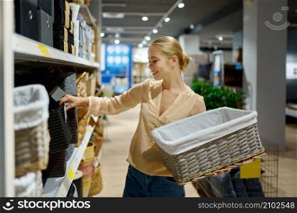 Woman buying wicker basket in shop standing and looking at camera.. Woman buying wicker basket standing in shop