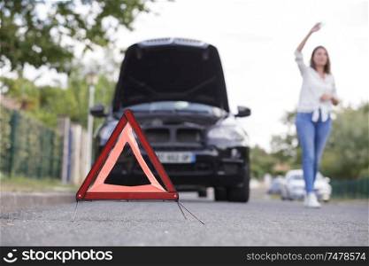woman by broken down car hailing help