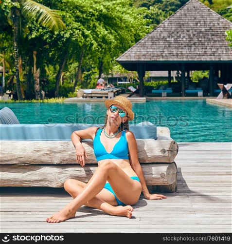 Woman by poolside. Resort swimming pool at Mahe, Seychelles.