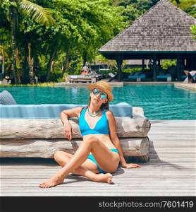 Woman by poolside. Resort swimming pool at Mahe, Seychelles.