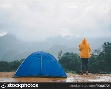 Woman c&ing blue tent on mountain peak and enjoying beautiful nature of hills and during rainy season at Doi Tapang, Sawi District, Chumphon, Thailand.
