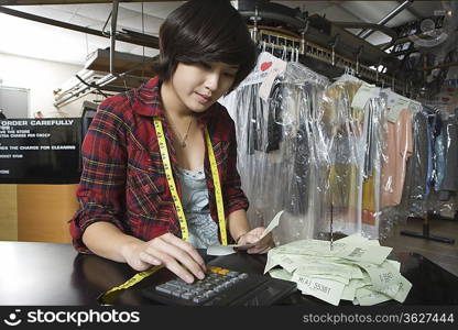 Woman calculating receipts in the laundrette