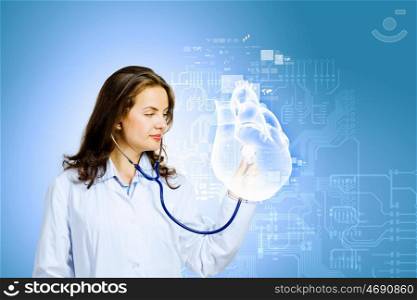 Woman cardiologist. Image of young woman cardiologist with stethoscope examining heart