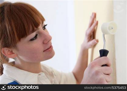 Woman carefully painting wall with roller