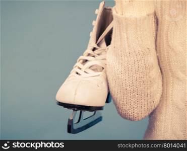 Woman carrying a pair of ice skates getting ready for ice skating, winter sport activity, on blue
