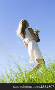 Woman carrying bouquet in tall grass