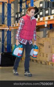 woman carrying cans of oil through warehouse