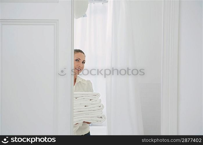 Woman carrying folded linen in home