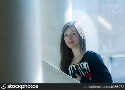 Woman carrying notebook looking at camera smiling