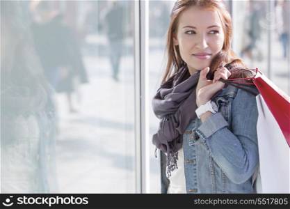 Woman carrying shopping bags while standing by store