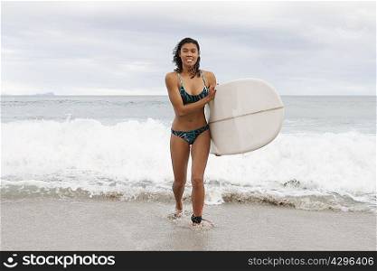 Woman carrying surfboard on beach