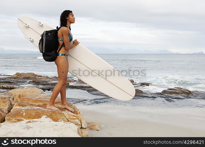 Woman carrying surfboard on beach