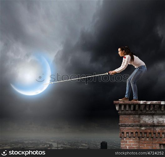 Woman catching moon. Young woman in casual catching moon with rope