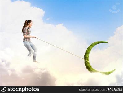 Woman catching moon. Young woman in casual catching moon with rope
