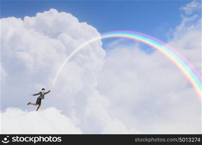 Woman catching rainbow. Young businesswoman in bowler hat and colorful rainbow in hand