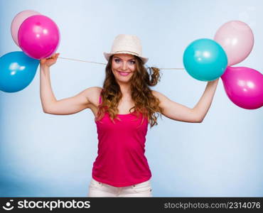 Woman charming girl playing with many colorful balloons. Summer, celebration happiness and lifestyle concept. Studio shot blue background. Woman playing with many colorful balloons