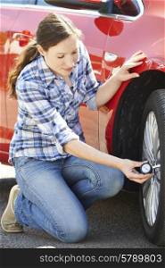 Woman Checking Car TyrePressure Using Gauge