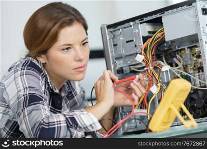 woman checking computer with a multimeter