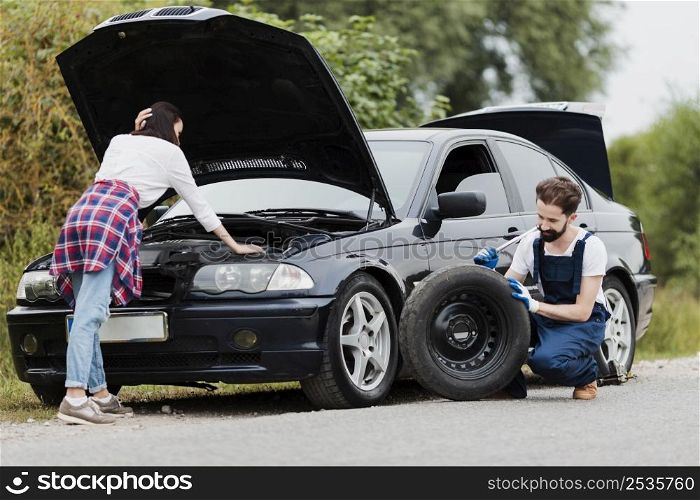 woman checking engine man changing tyre