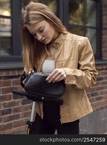 woman checking her bag while riding electric scooter outdoors