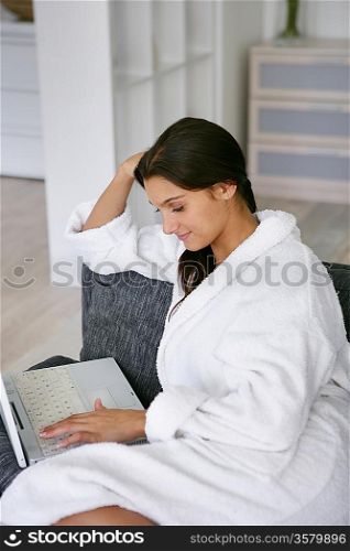 Woman checking her emails in her bathrobe