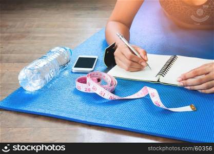 Woman checking her health after workout, Diet and Fitness concept with sport equipments
