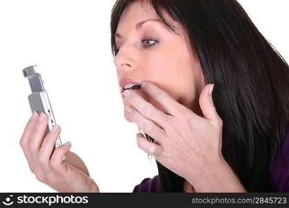 Woman checking her lipstick in the reflection on her cellphone