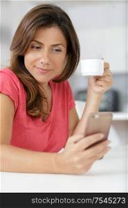 woman checking her phone while having a coffee
