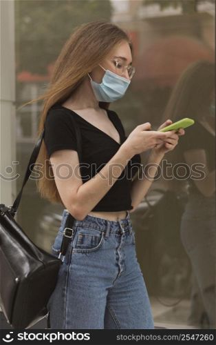 woman checking her phone while wearing medical mask