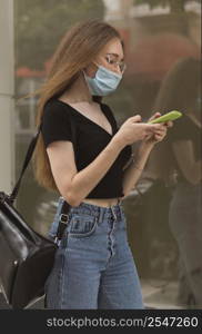 woman checking her phone while wearing medical mask