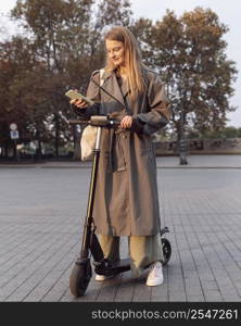 woman checking her smartphone while electric scooter outdoors