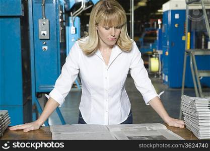 Woman checking newspaper in factory