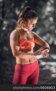 Woman checking progress on smart watch after training outdoors