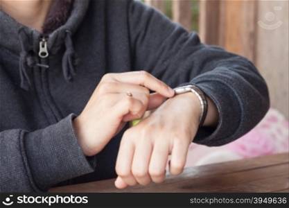 Woman checks the time on a wrist watch, stock photo