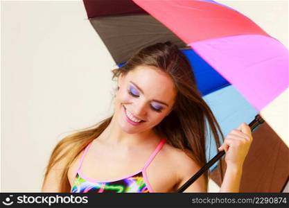 Woman cheerful summer girl standing under colorful rainbow umbrella, Attractive female long hair model. Forecasting and weather season concept. Woman standing under colorful rainbow umbrella