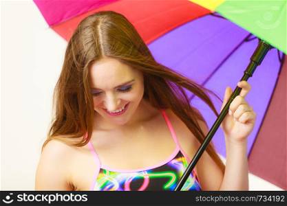 Woman cheerful summer girl standing under colorful rainbow umbrella, Attractive female long hair model. Forecasting and weather season concept. Woman standing under colorful rainbow umbrella
