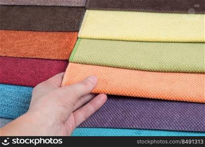 Woman chooses s&les of colored fabric on table close up. Woman chooses s&les of colored tissue