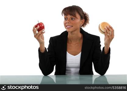 Woman choosing between apple and burger