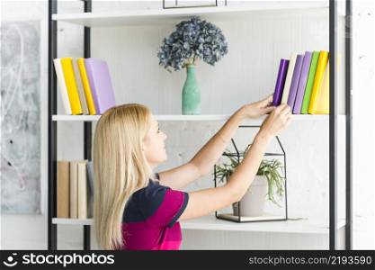 woman choosing book from shelf home